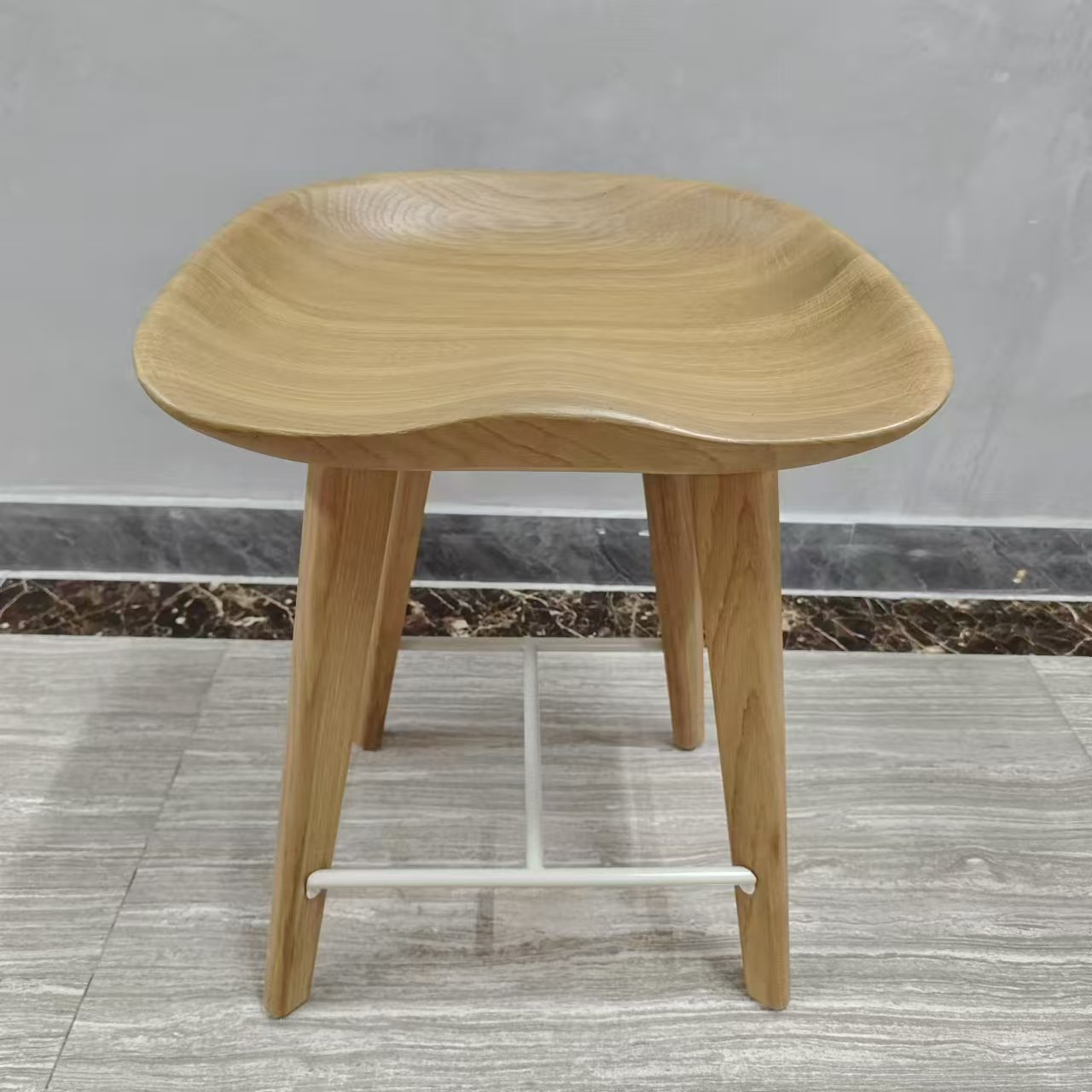 White oak saddle stool detail showing solid wood grain and curved seat by Dejell