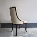 Close-up of white ash wood frame and curved leg detail on tufted dining chair