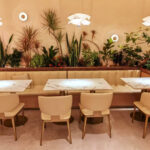 Restaurant dining area with custom beige booth seating and round marble tables by Dejell