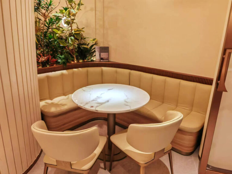 L-shaped booth seating with square marble tables and gold-base chairs in restaurant by Dejell