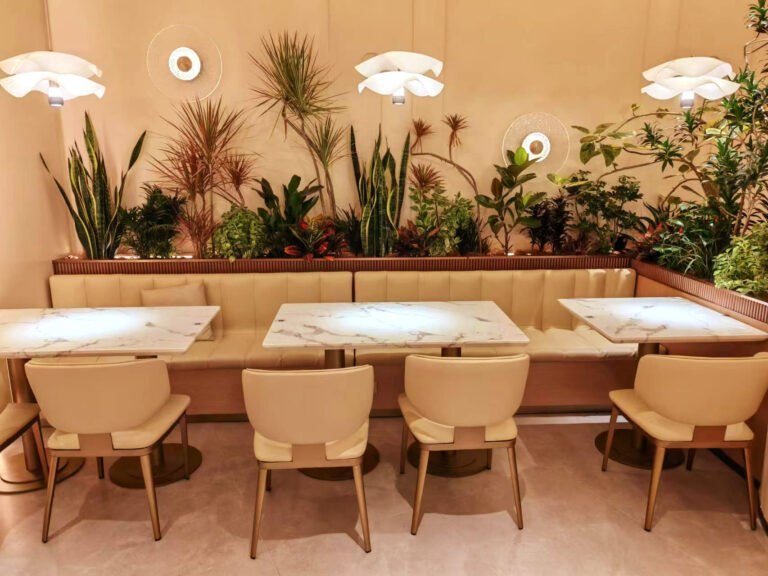 Restaurant dining area with custom beige booth seating and round marble tables by Dejell