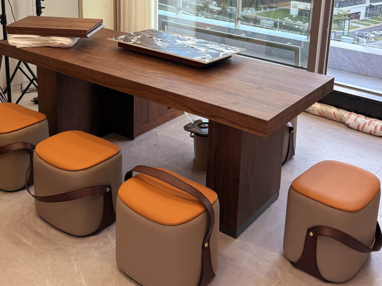 Walnut display table with cushioned ottoman stools in chamber lounge by Dejell