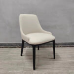 Modern cream white restaurant chair showing sculpted backrest and black wood legs from angled view by Dejell