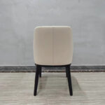 Back view of upholstered dining chair with curved high backrest and solid wood frame by Dejell