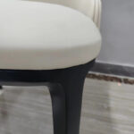 Seat cushion and black solid white ash wood leg connection detail on cream white dining chair by Dejell